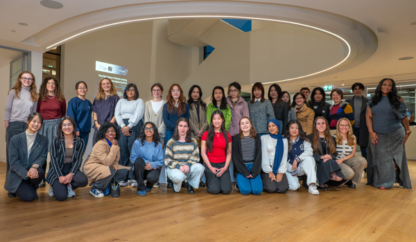 Group photo of more than thirty attendees from the Oxford and Cambridge Women in Engineering societies, including academics, researchers, students, event speakers and representatives from the sponsoring organisation, standing and sitting together inside the Jesus College Digital Hub.